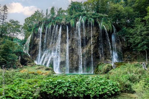 Low angle view of multiple waterfalls streaming into a beautiful, tranquil, clear lake at Plitvice Lakes National Park