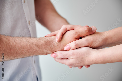 Close up of two hands engaging in delicate touch. Man's and woman's hands on white neutral background. Husband holding hand of his lovely wife. Concept of affection, support, and mutual respect.