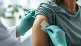 healthcare professional is applying a bandage to the upper arm of a patient after an injection or blood draw