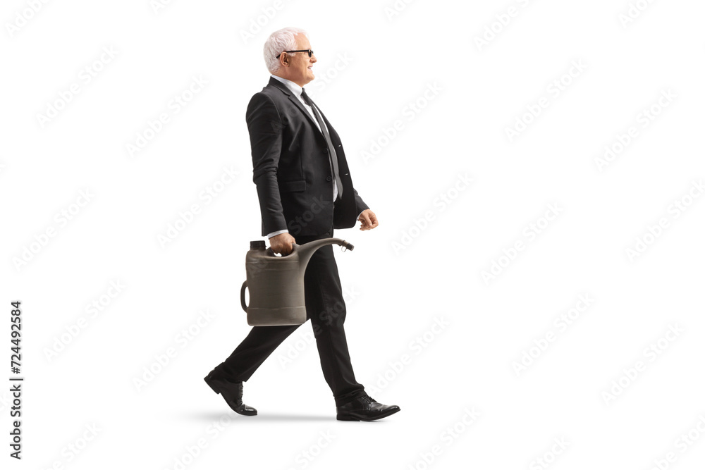 Full length profile shot of a mature businessman walking and carrying a gas canister Full length profile shot of a mature businessman walking and carrying a gas canister