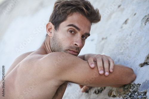 Man, serious and fitness body with arms, muscle and wellness outdoor by a wall. Summer, thinking and idea of a male person from Brazil with strong, relax and topless with confidence and calm