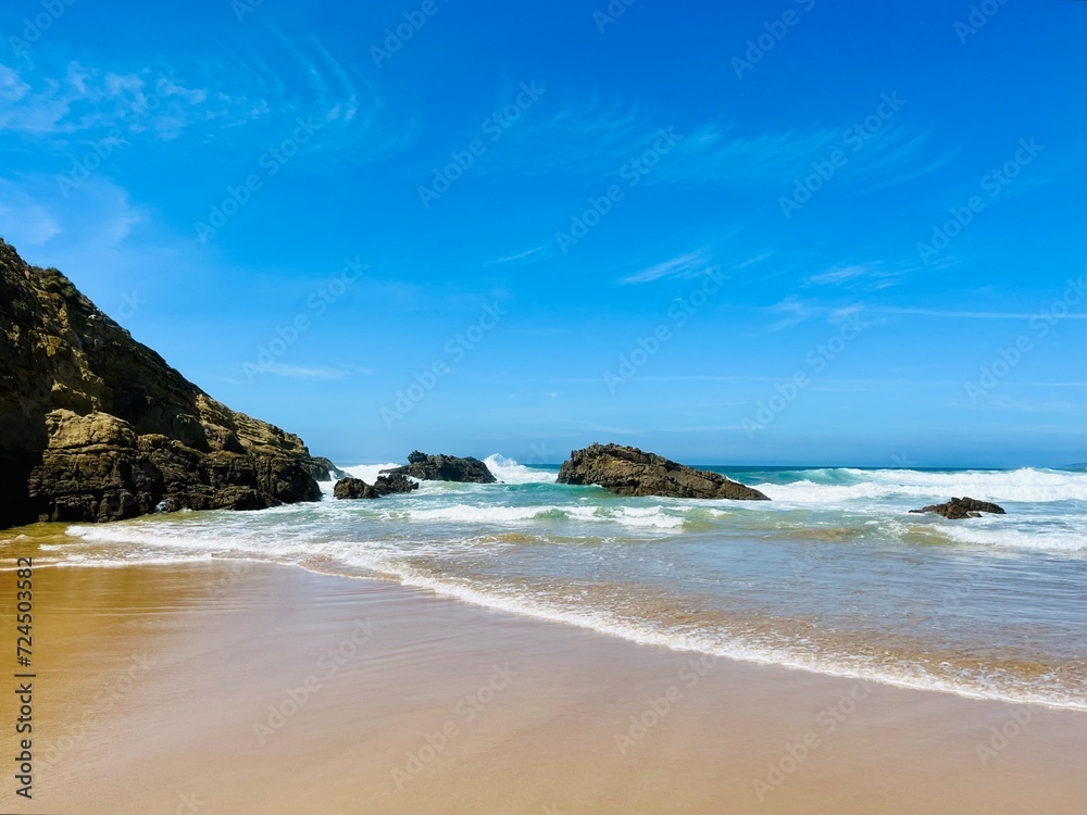 Fototapeta premium Rocky ocean coast, ocean bay with rocky coast and sand beach, blue sky, no people