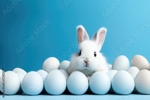 Cute bunny with Easter eggs on blue background with copy space. ai generated © dark_blade