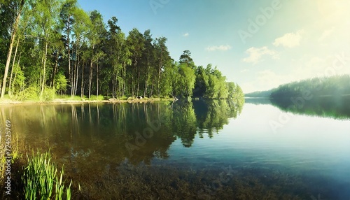 calm placid freshwater lake with dense trees forest on the shore