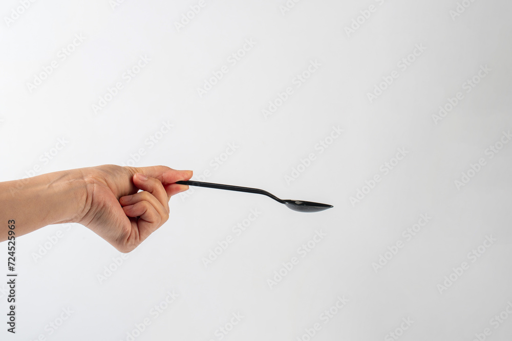 Black plastic spoon in hand on white background Black plastic spoon in hand on white background