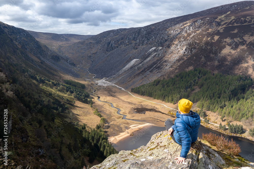 mountaineer sitting on a rock, looking at landscape of Wicklow mountains, ireland mountaineer sitting on a rock, looking at landscape of Wicklow mountains, ireland