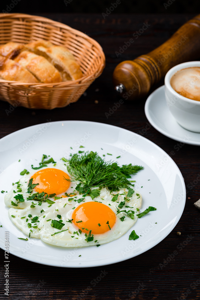 Fresh fried eggs with greens and a cup of coffee for breakfast.