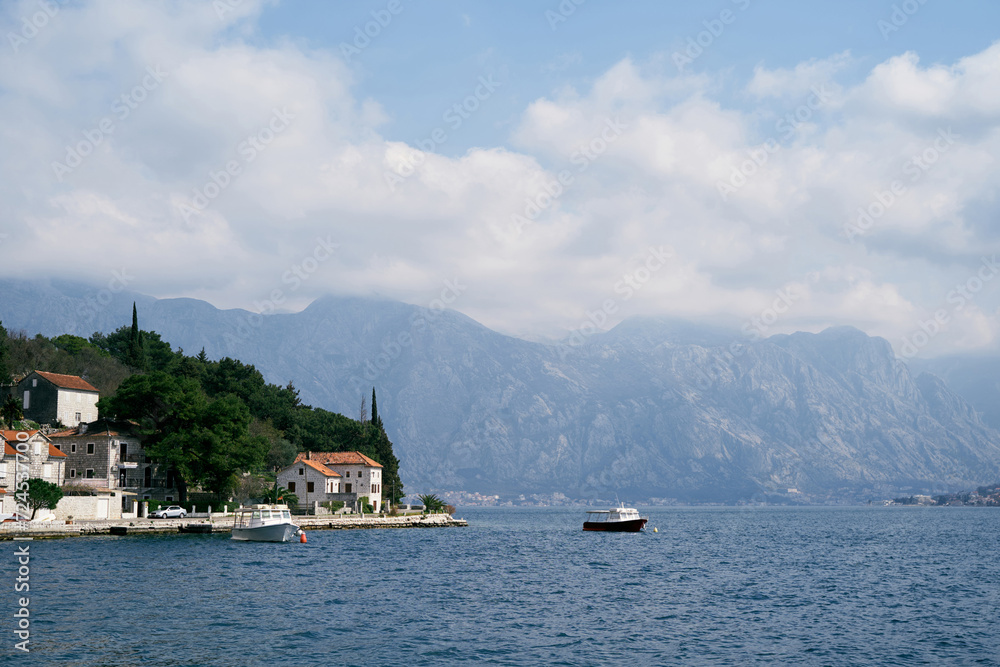 Motorboats are moored off the coast of Perast with old houses with red roofs. Montenegro
