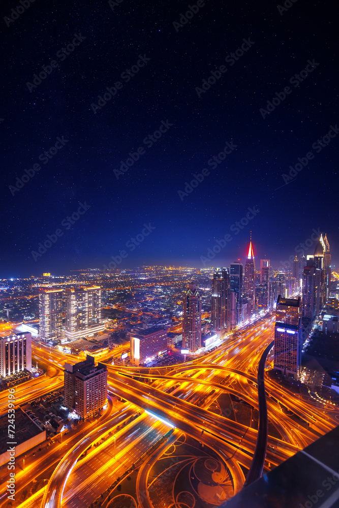 Night cityscape of center Dubai, aerial top view. Skyscrapers illuminated and highway of UAE