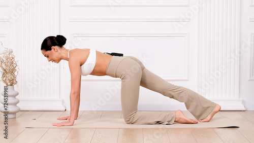 Fitness woman doing exercise for all muscle groups. An active girl is doing a workout on a light background. The concept of a healthy, beautiful female body.