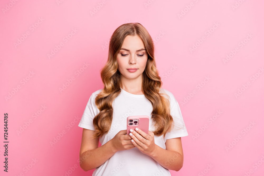 Photo of nice good mood woman with wavy hairstyle dressed white t-shirt read notification on smartphone isolated on pink color background Photo of nice good mood woman with wavy hairstyle dressed white t-shirt read notification on smartphone isolated on pink color background