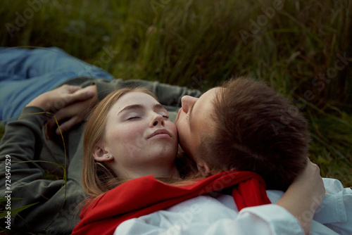 young teen couple laying on a grass on a field in september photo