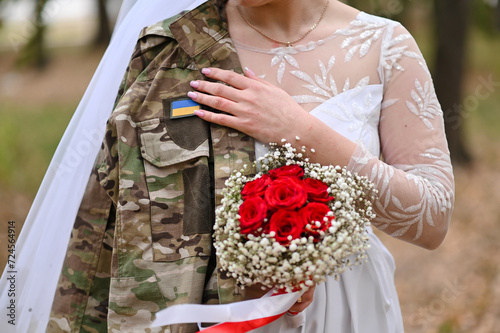 The bride holds the groom's military jacket. The concept