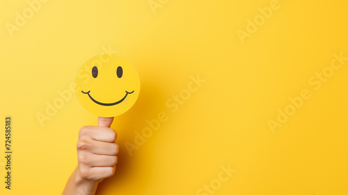 a yellow paper smiley face on a yellow background, thumbs up  photo