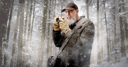 Homme photographe aventurier qui prend des photos dans une forêt en hiver sous la neige