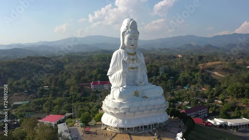 Aerial circling around Wat Huay Pla Kang giant white big statue and pagoda temple with mountains and landspace in Chiang Rai, Thailand. photo