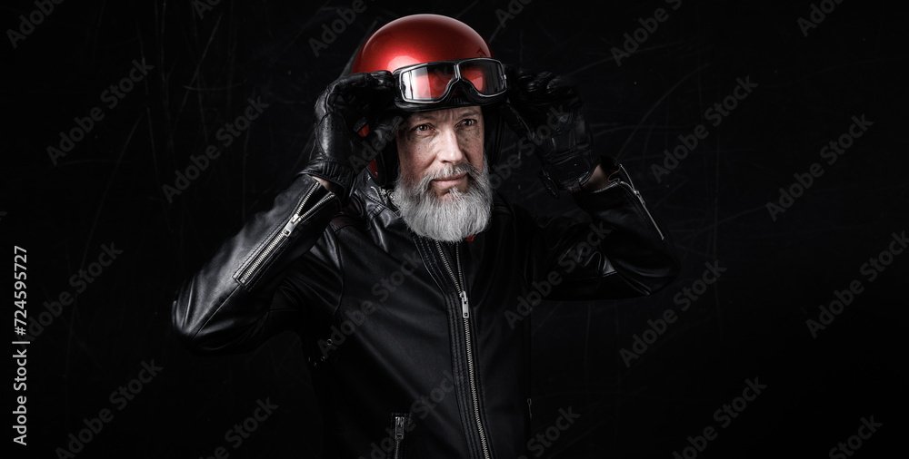 Portrait d'un motard homme avec un casque et une veste en cuir et des lunettes de protection et une barbe grise vintage Portrait d'un motard homme avec un casque et une veste en cuir et des lunettes de protection et une barbe grise vintage