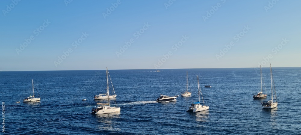 Obraz premium Beautiful seascape with yacht near shore in the sea. Modern sailboat on a sunny summer day. Sailing near coastline in the Mediterranean Sea. Scenic Amalfi Coast view.