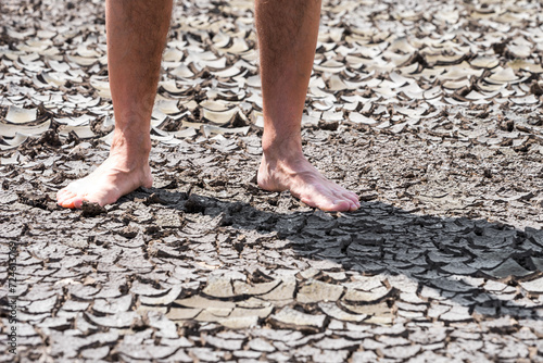bare feet of a person on dry soil without plants close up © Sofiia