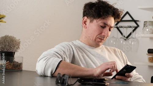 Young Caucasian man browsing his phone in the kitchen