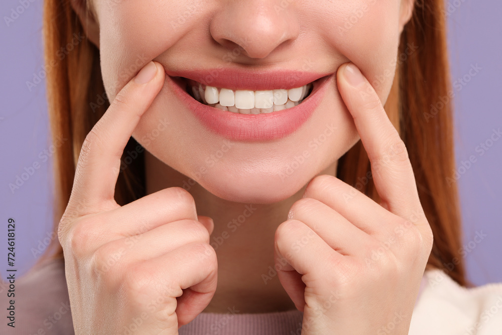 Woman showing her clean teeth and smiling on violet background, closeup Woman showing her clean teeth and smiling on violet background, closeup