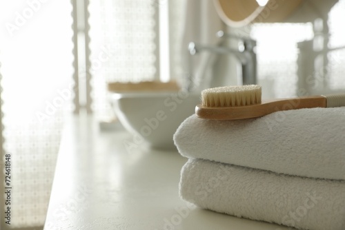 Stack of clean towels and massage brush on countertop in bathroom. Space for text
