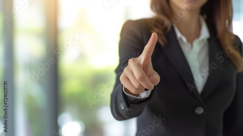 businesswoman pointing in office environment, front view
