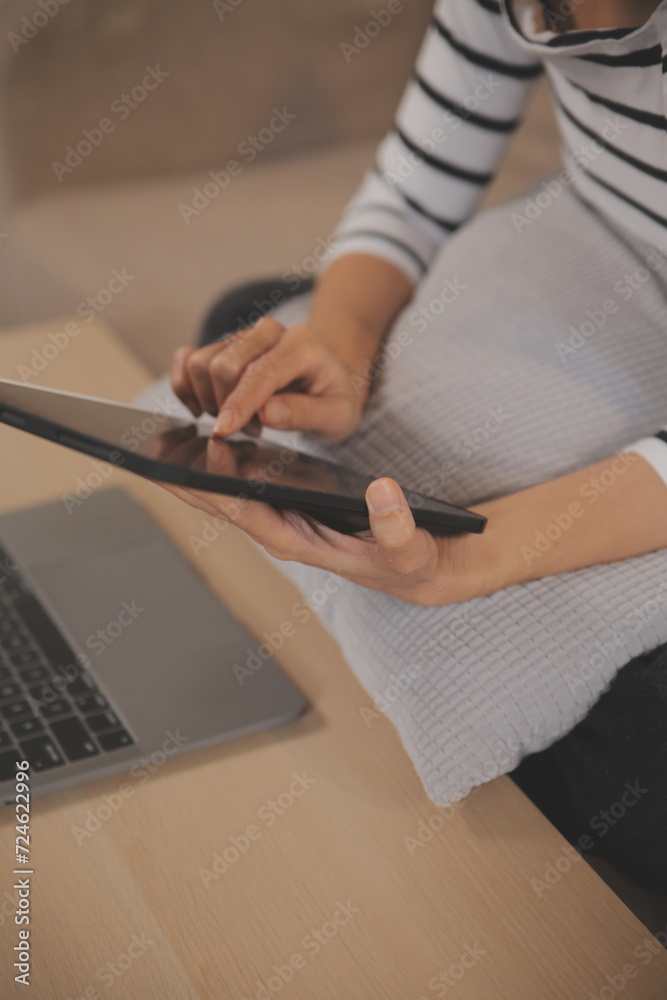 Naklejka premium Young attractive asian woman resting using browsing tablet computer on sofa at home, happy girl sitting on couch relax reading digital gadget with excited, communication and lifestyle concept.