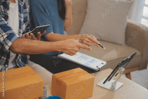 Two Asian blogger showing clothes in front of the camera to recording vlog video live streaming at her shop. Online Shopping Cart notion. on sofa at home