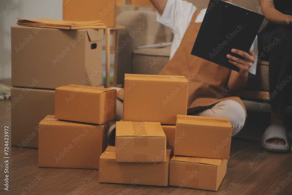 Two Asian blogger showing clothes in front of the camera to recording vlog video live streaming at her shop. Online Shopping Cart notion. on sofa at home