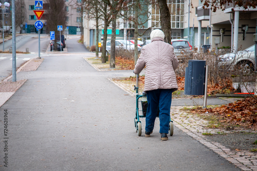 elder woman walkoing streets with a rollator