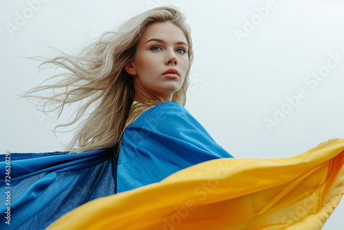 Blonde woman with flowing hair in blue and yellow cape against the sky