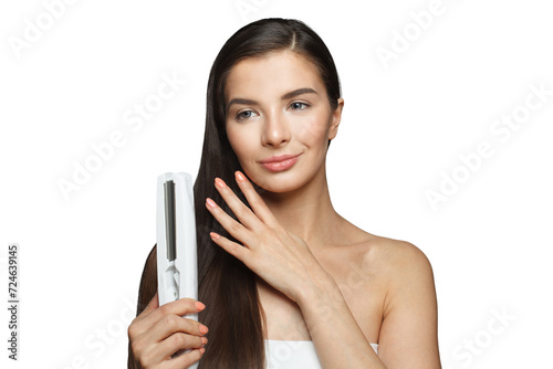 Nice model woman holding hair iron and straightening her healthy long dark hair isolated on white background. Haircare and hair styling concept