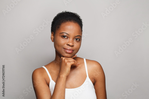 Calm African American female model with healthy fresh clear dark skin posing on white background. Skin care, cosmetology and beauty treatment