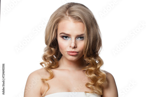 Sexy woman with clean fresh skin and long curly hair looking at camera on white studio wall background, portrait
