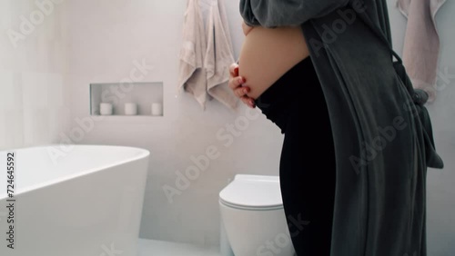 Pregnant woman standing on bathroom scale photo