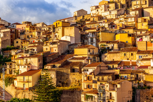 old vintage mediterranean mountain town with yellow and orange roofs, old tradirional streets, churches and amazing cloudy landscape on background