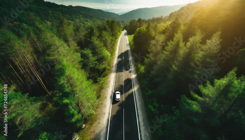aerial view asphalt road in the middle fores with car asphalt road through the mountain and green forest photo