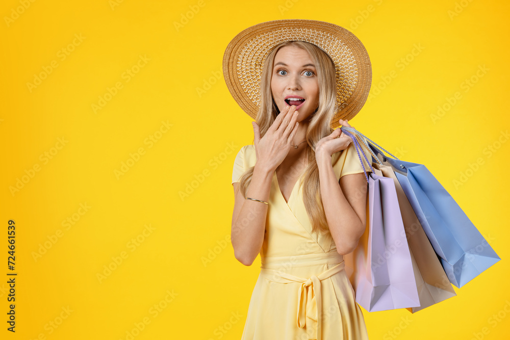 Portrait of shocked girl in dress holding shopping bags and looking at camera isolated over yellow background. Sale discount offer black Friday concept Portrait of shocked girl in dress holding shopping bags and looking at camera isolated over yellow background. Sale discount offer black Friday concept