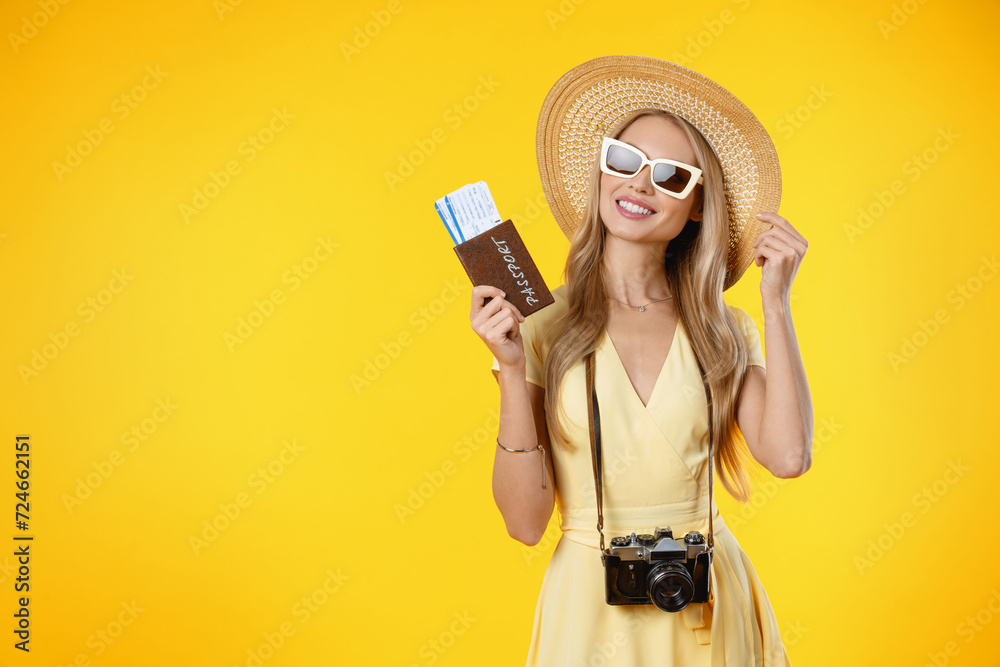 Tourist woman smiling while holding retro camera and travel tickets isolated over yellow background. Trip holiday voyage to foreign country abroad concept - obrazy, fototapety, plakaty 