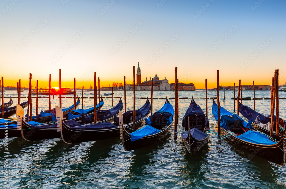 Gondolas moored by Saint Mark square against San Giorgio di Maggiore church in Venice, Italy.