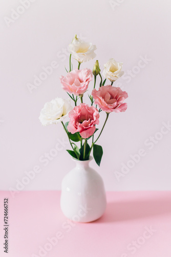Beautiful white and pink Eustoma  Lisianthus  flowers in a vase on a pink pastel background.