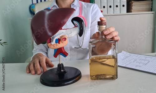 Alcohol liver damage and liver cirrhosis concept with liver with flask of alcohol in hands of doctor photo