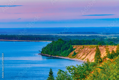 Seascape - the shore of Lake Onega in selective focus against the background of clouds at sunset.Karelian landscape.Concept of traveling around the Russian North.Nature, ecotourism.Forest lake. photo