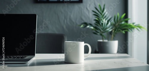 Empty white mug by a tilted laptop for a dynamic workspace. © AB malik
