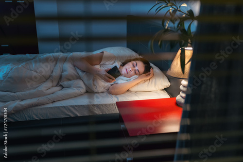 Obraz na plátne Someone is peeping through the blinds on window at woman lying in bed in her bedroom
