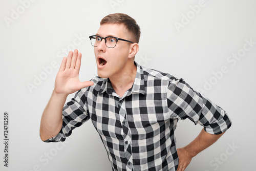 Portrait of handsome man shouting loudly with hands, news, palms folded like megaphone isolated on white background