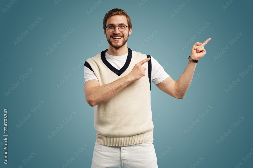 handsome man with beard pointing in one direction on a blue background. handsome man with beard pointing in one direction on a blue background.