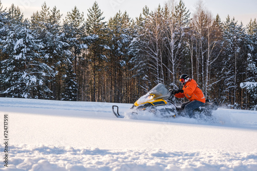 Athlete on a snowmobile moving in the winter forest in the mountains of the Southern Urals