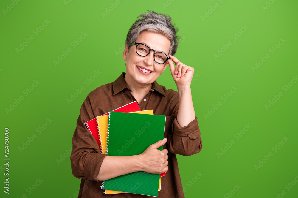 Portrait of smart person with white gray hairstyle touch glasses hold notebooks prepare for lecture isolated on green color background Portrait of smart person with white gray hairstyle touch glasses hold notebooks prepare for lecture isolated on green color background